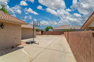 View of patio featuring driveway, a fenced backyard, an outbuilding, and a storage unit