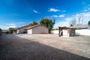 View of front of property with a garage, driveway, a shed, stucco siding, and an outdoor structure