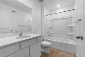 Bathroom featuring toilet, wood finished floors, shower / bath combination, and vanity