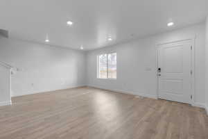 Unfurnished living room with light wood-type flooring, recessed lighting, and baseboards