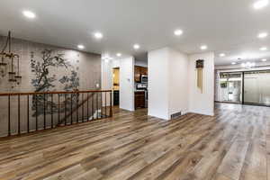 Spare room with a chandelier, wood finished floors, recessed lighting, and baseboards