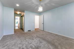 Spare room with carpet floors, baseboards, and a chandelier