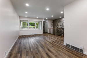 Spare room featuring recessed lighting, dark wood finished floors, and baseboards