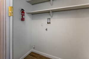Clothes washing area with baseboards, washer hookup, and dark wood-type flooring