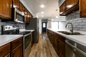 Kitchen with stainless steel appliances, a sink, light countertops, dark wood-style flooring, and recessed lighting
