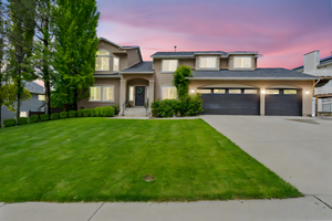 View of front of house featuring driveway, stucco siding, a yard, and an attached garage