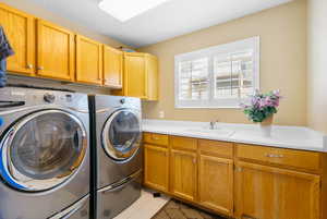 Laundry area featuring washing machine and dryer, cabinet space, and light tile patterned floors