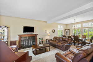 Carpeted living area with a tile fireplace, a chandelier, and beam ceiling