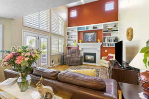 Living area with a high ceiling, a tile fireplace, and wood finished floors