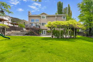Rear view of house with stairway, a playground, a deck, stucco siding, and a patio area