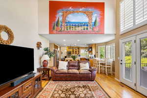Living room featuring a towering ceiling, light wood-style floors, and recessed lighting