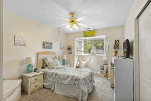 Bedroom featuring light carpet, a ceiling fan, a textured ceiling, and baseboards