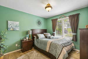 Bedroom with baseboards, wood finished floors, and a textured ceiling