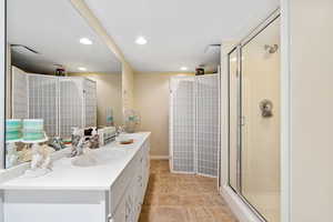Full bathroom with a stall shower, double vanity, recessed lighting, and baseboards