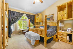 Carpeted bedroom featuring lofted ceiling and a ceiling fan