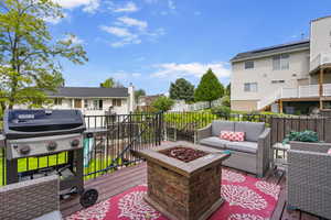 Wooden terrace featuring an outdoor living space with a fire pit, a fenced backyard, a residential view, and a grill