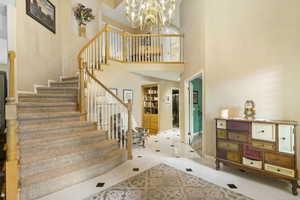 Stairway featuring tile patterned floors, a chandelier, baseboards, and a towering ceiling