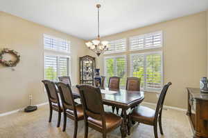 Dining space featuring a chandelier, baseboards, and light carpet