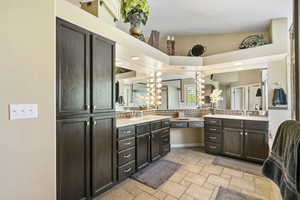 Bathroom featuring stone tile floors, two vanities, and a chandelier