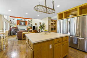 Kitchen with open shelves, freestanding refrigerator, light wood-style flooring, a kitchen island, and light countertops
