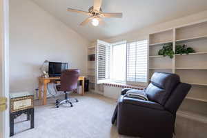 Carpeted office with lofted ceiling and a ceiling fan