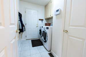 Laundry room featuring cabinet space, washing machine and dryer, and light tile patterned flooring