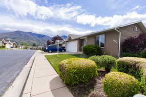 View of side of property featuring brick siding, a mountain view, an attached garage, and driveway