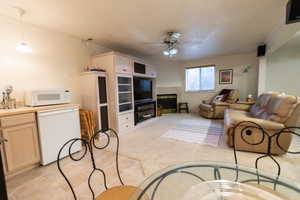 Living room with ceiling fan, crown molding, and light carpet