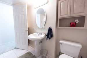 Bathroom with tile patterned flooring, toilet, and baseboards