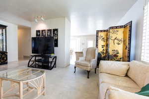 Living area with light carpet and a textured ceiling