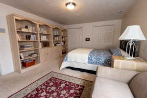 Bedroom featuring two closets, a textured ceiling, and carpet floors