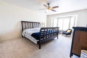 Carpeted bedroom featuring wallpapered walls, ceiling fan, and baseboards