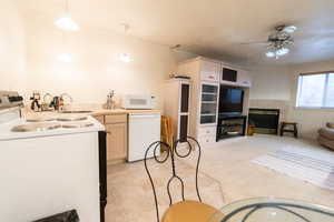 Kitchen with white appliances, a sink, ceiling fan, a tile fireplace, and pendant lighting