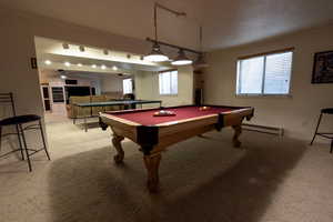 Recreation room featuring crown molding, light colored carpet, pool table, and baseboard heating