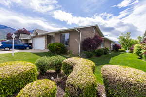 View of front facade featuring an attached garage, brick siding, a front yard, a mountain view, and driveway