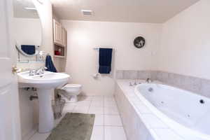 Bathroom with a whirlpool tub, tile patterned floors, toilet, and baseboards