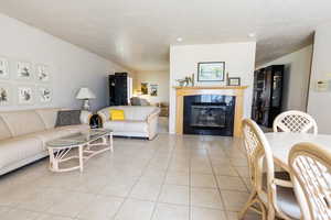 Living room featuring a tiled fireplace, light tile patterned flooring, and a textured ceiling