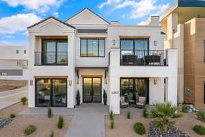 View of front of property featuring a balcony, stucco siding, and french doors