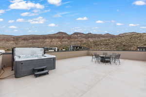 View of patio / terrace with outdoor dining area, a mountain view, and a hot tub