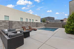 View of swimming pool featuring patio surround, a fenced backyard, and an outdoor living space with a fire pit