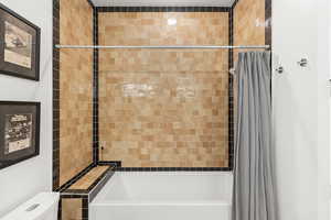 Bathroom featuring shower / tub combo with curtain and toilet