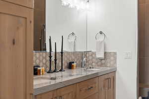 Bathroom featuring double vanity and decorative backsplash