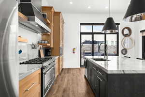 Kitchen featuring appliances with stainless steel finishes, open shelves, wall chimney range hood, light stone countertops, and recessed lighting