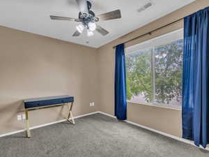 Carpeted spare room with baseboards, a ceiling fan, and visible vents