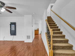 Stairway featuring ceiling fan, baseboards, visible vents, and wood finished floors