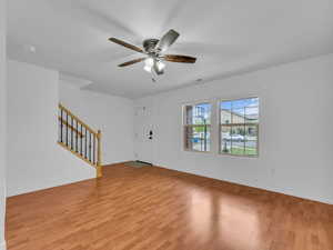 Interior space featuring stairway, ceiling fan, light wood-style flooring, and baseboards