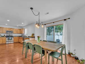 Dining area with light wood-type flooring, a wealth of natural light, an inviting chandelier, and recessed lighting
