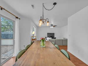 Dining room with a ceiling fan, baseboards, visible vents, and wood finished floors