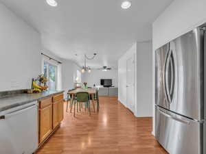 Kitchen with freestanding refrigerator, dark countertops, dishwasher, light wood-style floors, and recessed lighting