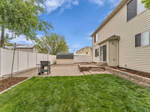 View of yard featuring an outdoor structure, a storage unit, a patio, a fenced backyard, and entry steps